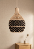 A pendant light woven from natural rattan, featuring interlocking black geometric patterns that give the place a warm Bohemian feel.