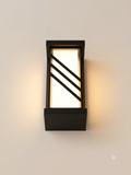 A rectangular black wall sconce with a modern geometric design, featuring slanted metal lines that cut across its illuminated face to provide warm and attractive lighting.