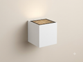 A white cube-shaped wall sconce with a metal top grille to direct the light upwards.