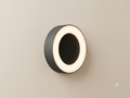 A black circular wall sconce with a simple, modern design, featuring a bright white LED light ring.