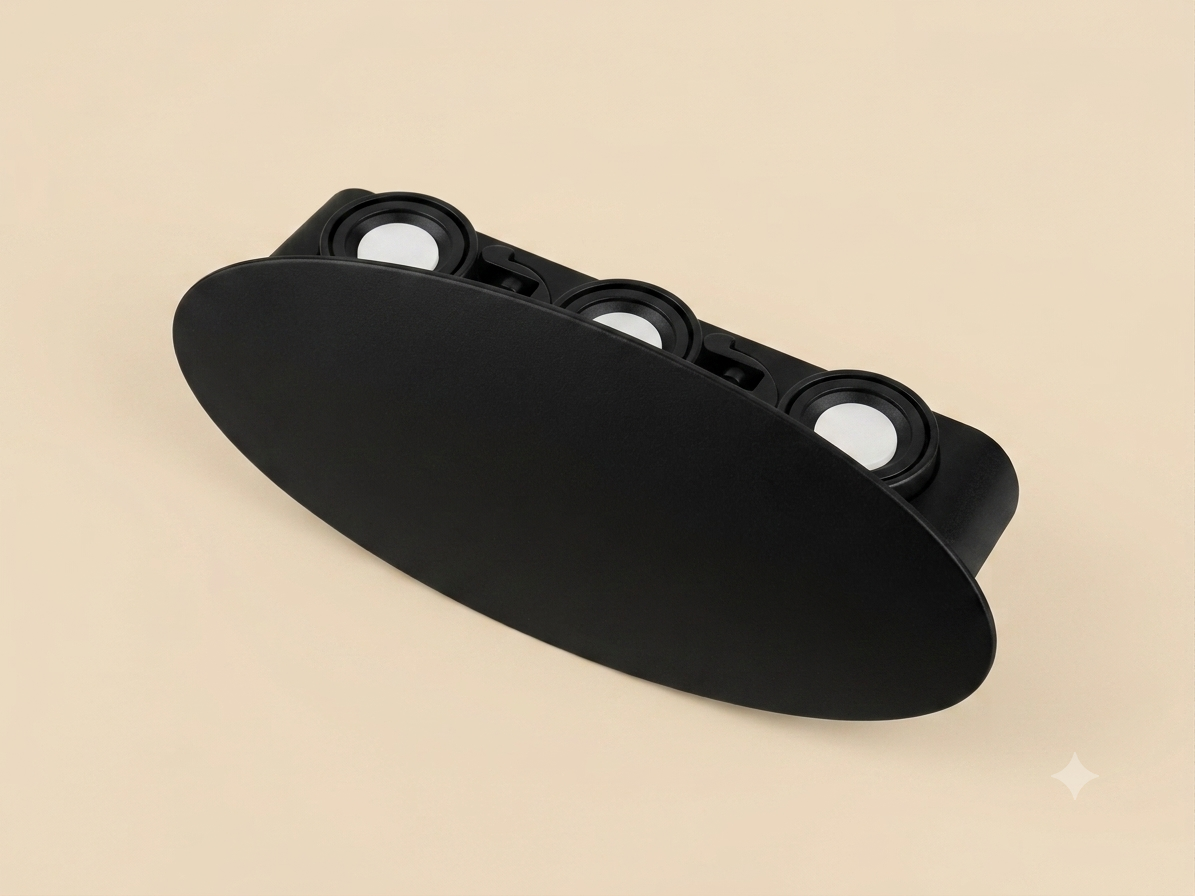 A black, flat oval-shaped wall sconce that hides three circular light lenses to provide indirect lighting.