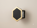 A wall sconce with a hexagonal geometric design, featuring a black front and a gold frame.
