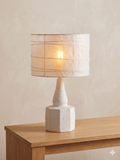 A modern table lamp (bed lamp) with a white ceramic base and a paper shade that emits warm light.