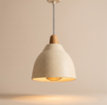 A pendant light unit with a streamlined design inspired by natural shapes, combining the warmth of wood and the dotted ceramic texture to add a calming touch to the architectural space.
