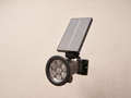 Solar-powered outdoor lighting unit with a top solar panel and multiple LED lights.