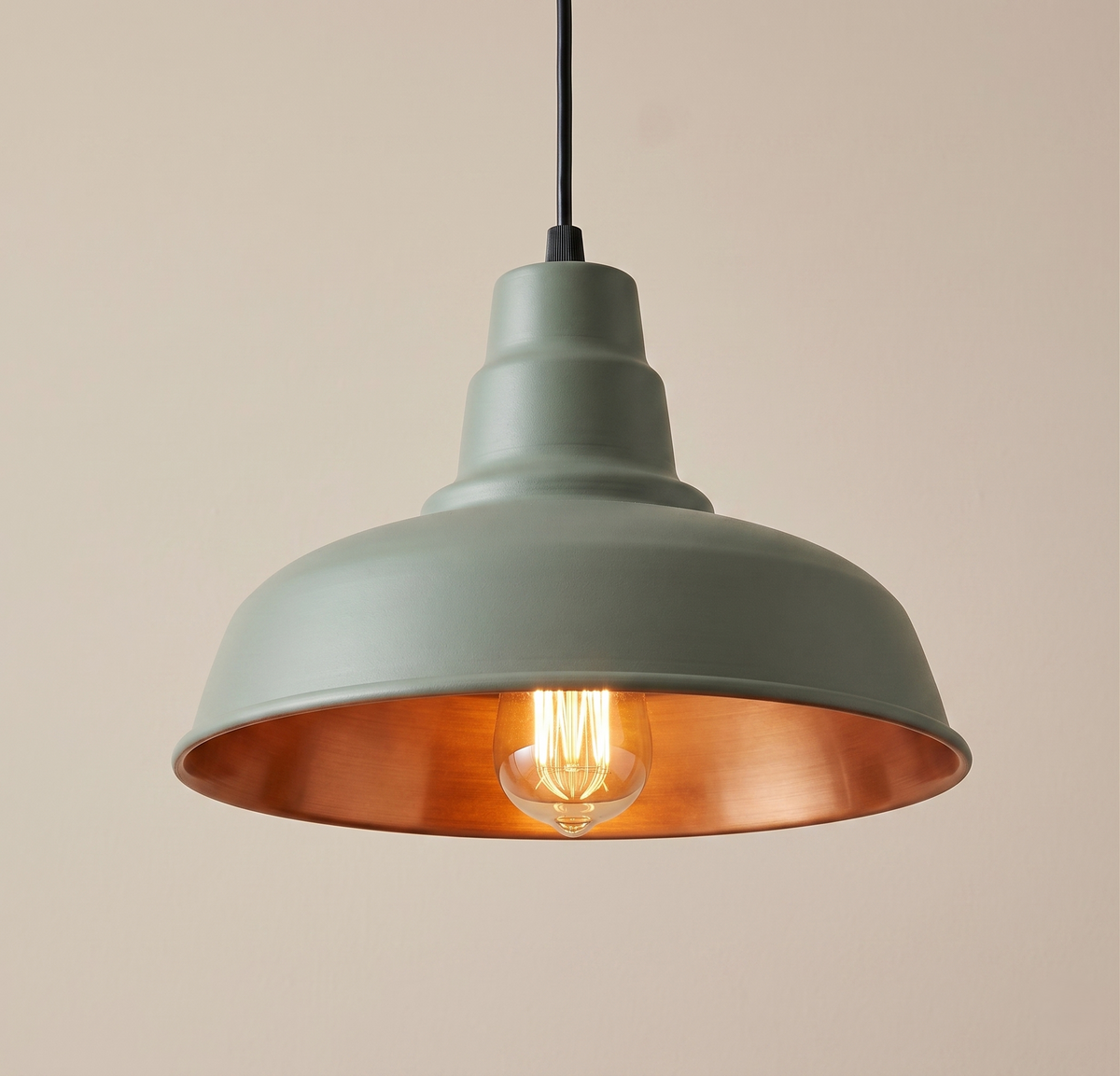 An industrial-style pendant light unit, combining a matte green exterior finish and a warm copper lining to reflect rich and comfortable light.