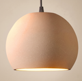 A pendant light with a spherical design and dotted ceramic texture, reflecting the warmth of earthy colors and adding an organic and attractive touch to the space.