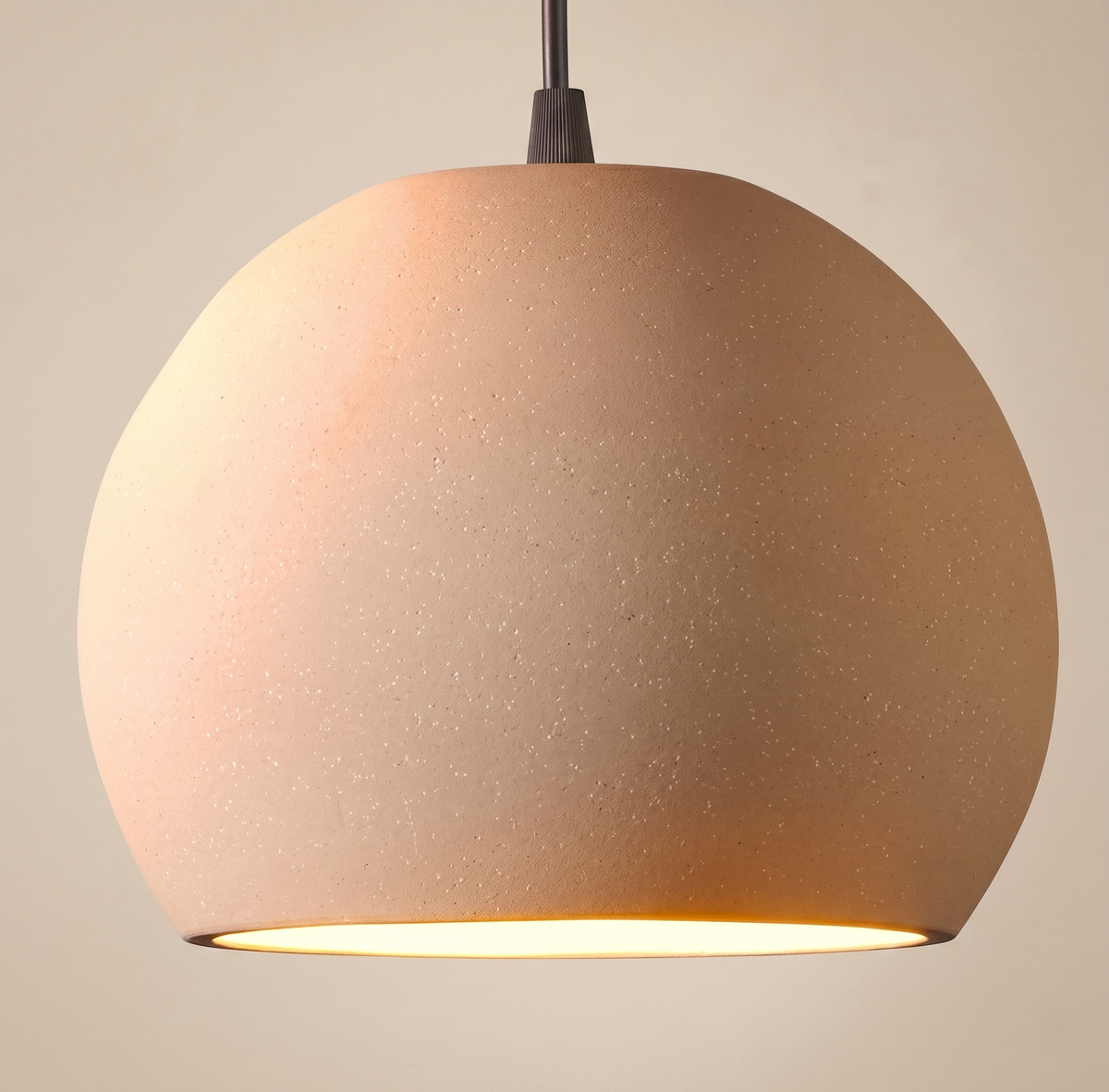 A pendant light with a spherical design and dotted ceramic texture, reflecting the warmth of earthy colors and adding an organic and attractive touch to the space.