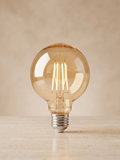 Spherical LED filament lamp with a warm gold finish.