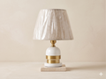 A modern table lamp made of white and gold ceramic with a light marble base.