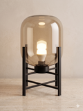 A modern glass table lamp on a black metal stand.